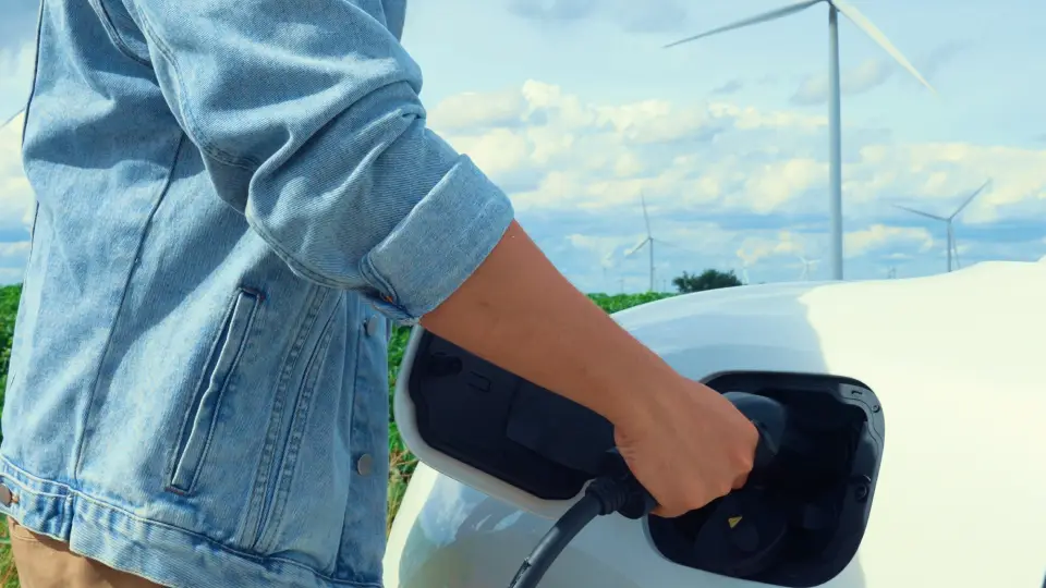 E-Auto wird geladen vor Windrädern