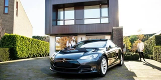 Tesla vor Backsteinhaus mit Wallbox an der Wand