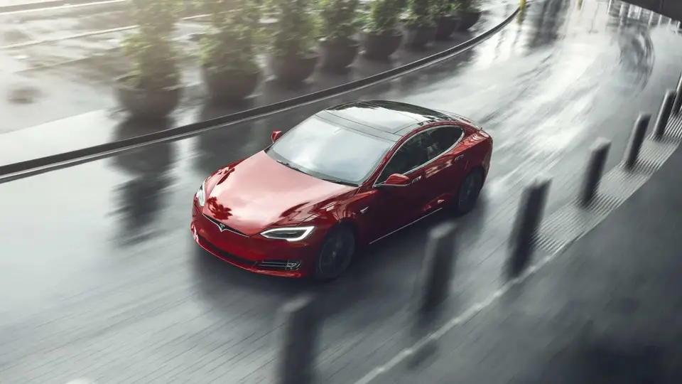 Elektro Limousine Tesla Model S in rot auf Straße bei Regen