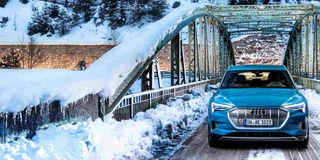 Frontansicht des Audi etron in der Farbe blau auf einer Brücke im Winter mit Allrad