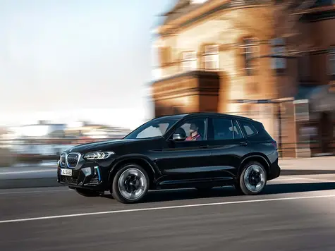 BMW iX3 Elektroauto in der Farbe Blau Ansicht von schräg vorne während einer Stadtfahrt