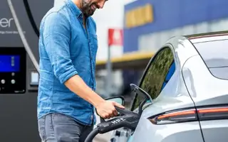 Mann lädt Firmenwagen mit Ladekarte