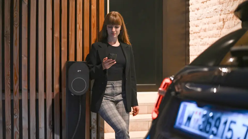 Frau steht neben AFIR-fähigem go-e Charger Core