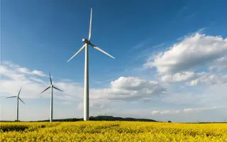 Windräder vor einem Feld fuer flexible Stromvertraege