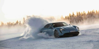 Ansicht Porsche Taycan in der Farbe Blaugrau mit Akzenten von schräg Vorne bei Schneefahrt