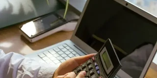 150 kw in PS - Frauenhand mit Taschenrechner vor Laptop