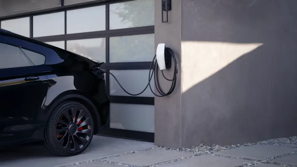 Tesla Wallbox lädt schwarzes Elektroauto vor moderner Garage