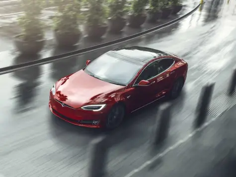 Tesla Model S Elektroauto in der Farbe rot Ansicht von schräg Oben während der Fahrt