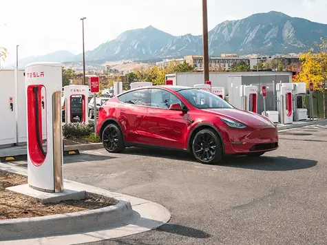 Tesla Model Y in Farbe rot beim Laden am Supercharger
