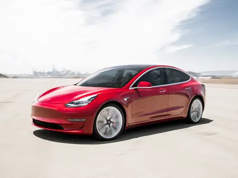 Tesla Model 3 Elektroauto in der Farbe rot Ansicht von schräg Vorne im Stand