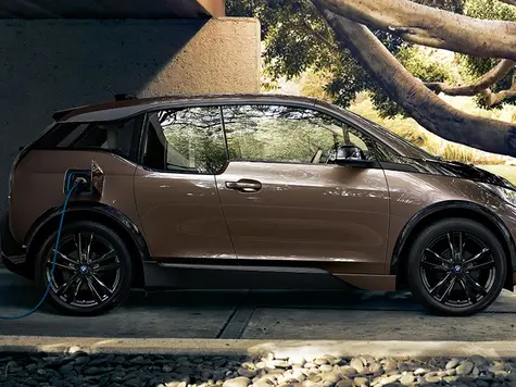 BMW i3 Elektroauto in der Farbe Braun Ansicht von schräg Hinten in der Fahrt