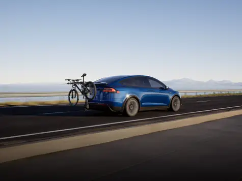 Tesla Model X Elektroauto in der Farbe blau Ansicht von schräg Hinten während der Fahrt