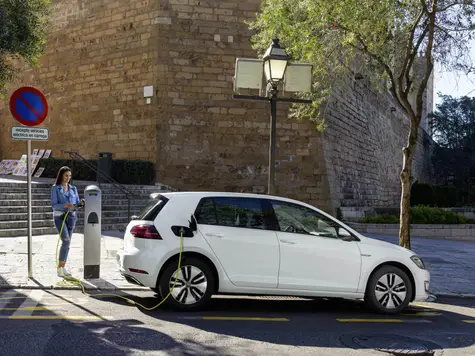 VW e-Golf Elektroauto in der Farbe weiss Ansicht von der Seite beim Laden an einer Ladesäule